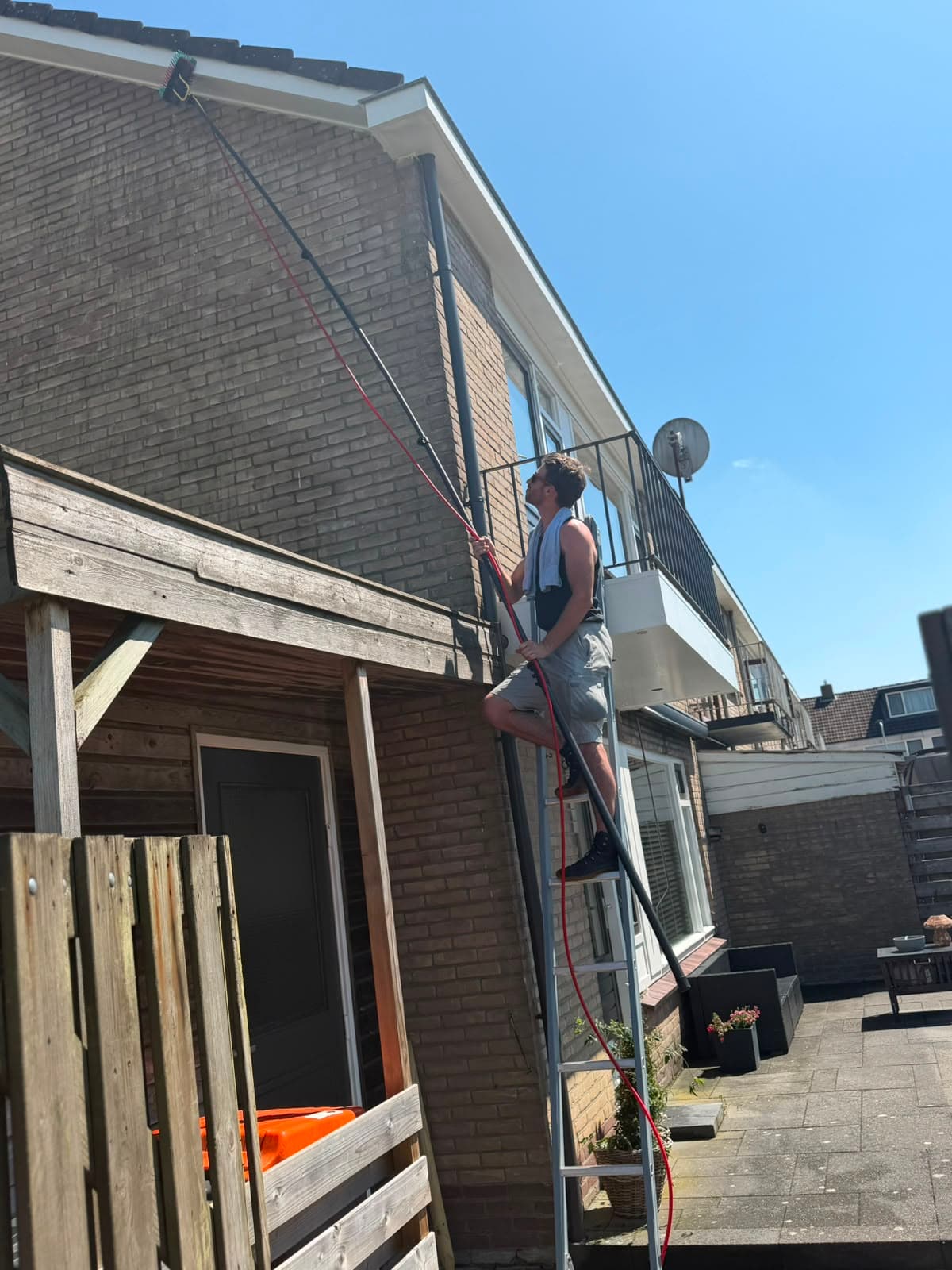 Dakgoot van een woning in Apeldoorn wordt vanaf een ladder gereinigd met een watergevoede telescoopsteel